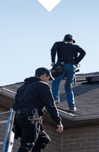 American Eagle Home Improvement roofing contractors standing on top of a gray shingle roof performing a roof replacement