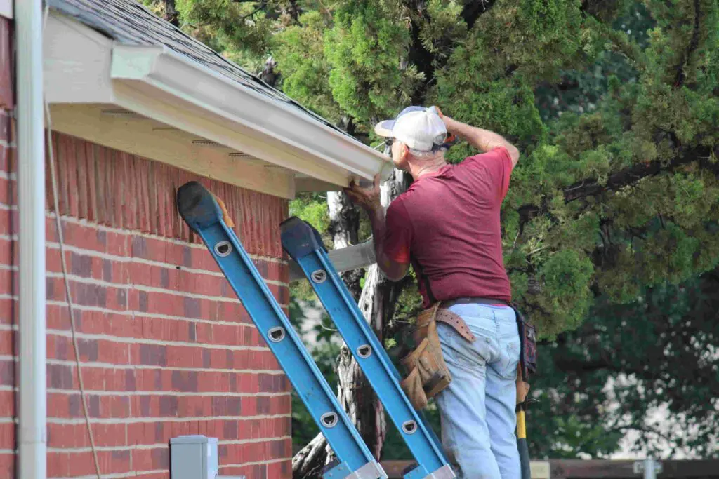 man performing gutter replacement on Minnesota home