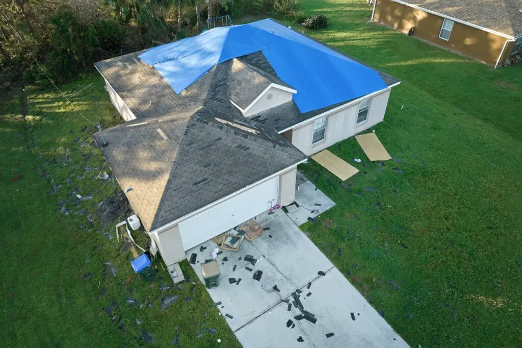 hail damaged house covered in a blue tarp