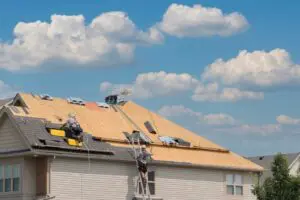 Roofers completely replace old asphalt shingle roof during summer