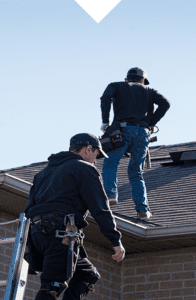 American Eagle Home Improvement roofing contractors standing on top of a gray shingle roof performing a roof replacement